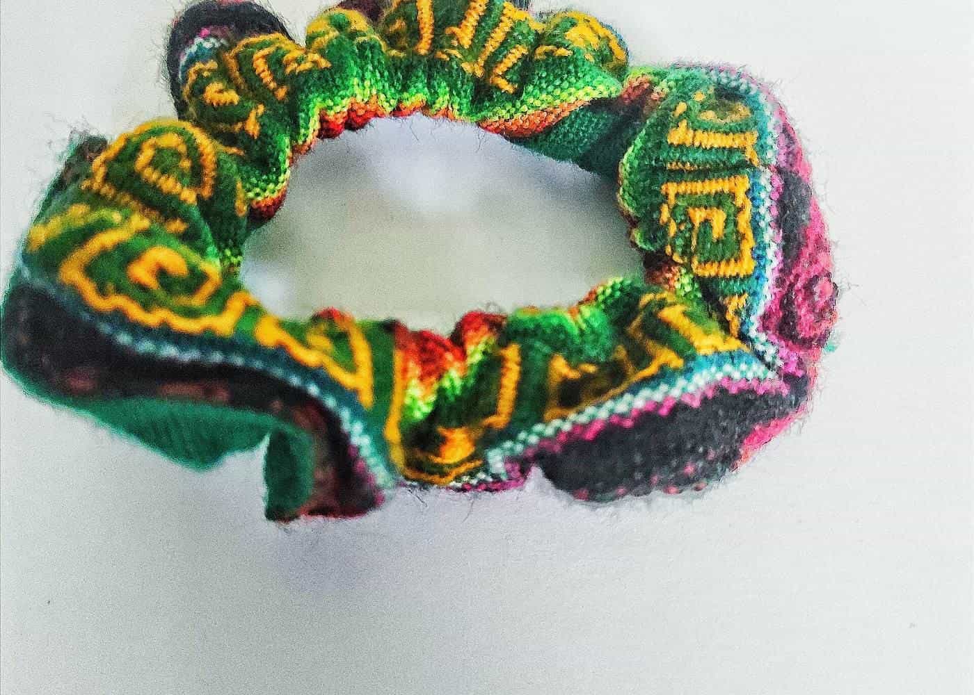 A colourful handwoven scrunchie on a white background