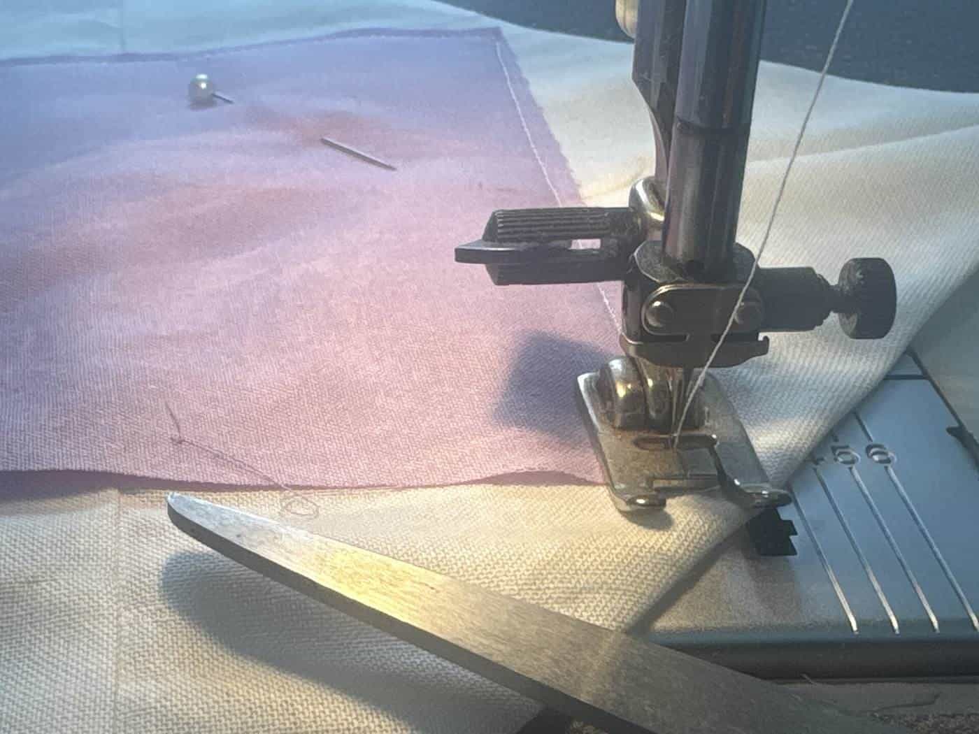 A sewing machine needle stitching pink and white fabric