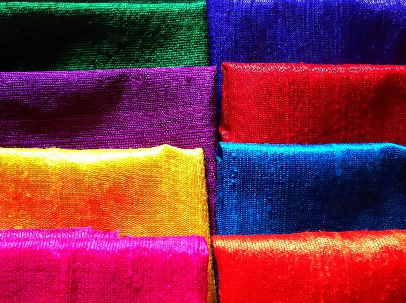 Bolts of brightly coloured silk fabric stacked in a shop